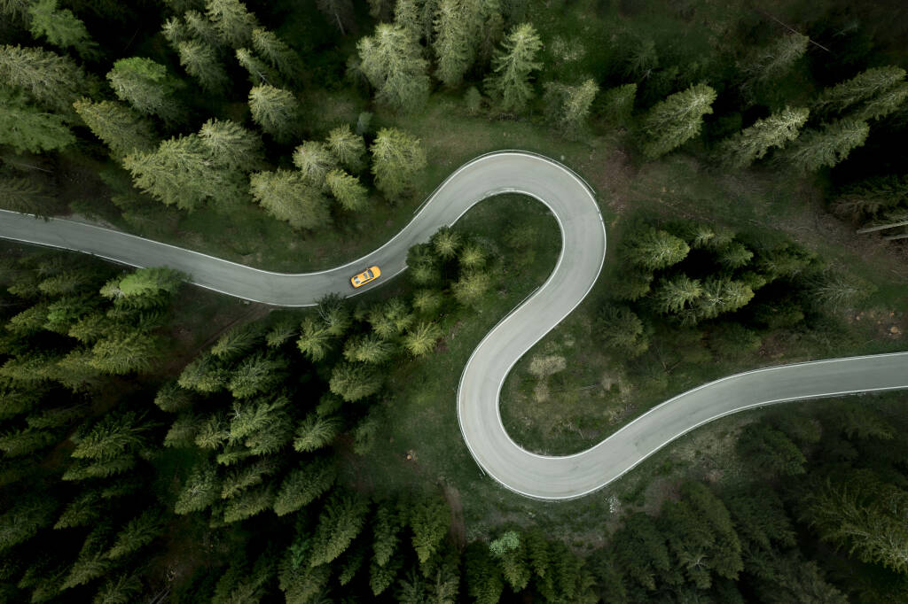 Aerial view of car traveling on winding mountain road in a forest